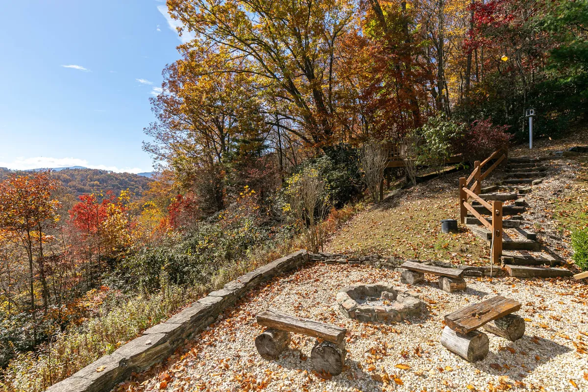 A cozy fire pit area with wooden benches is nestled amidst tall trees, creating an inviting spot for evening gatherings. The space is perfect for roasting marshmallows, sharing stories, or simply enjoying a mountain sunset with loved ones.