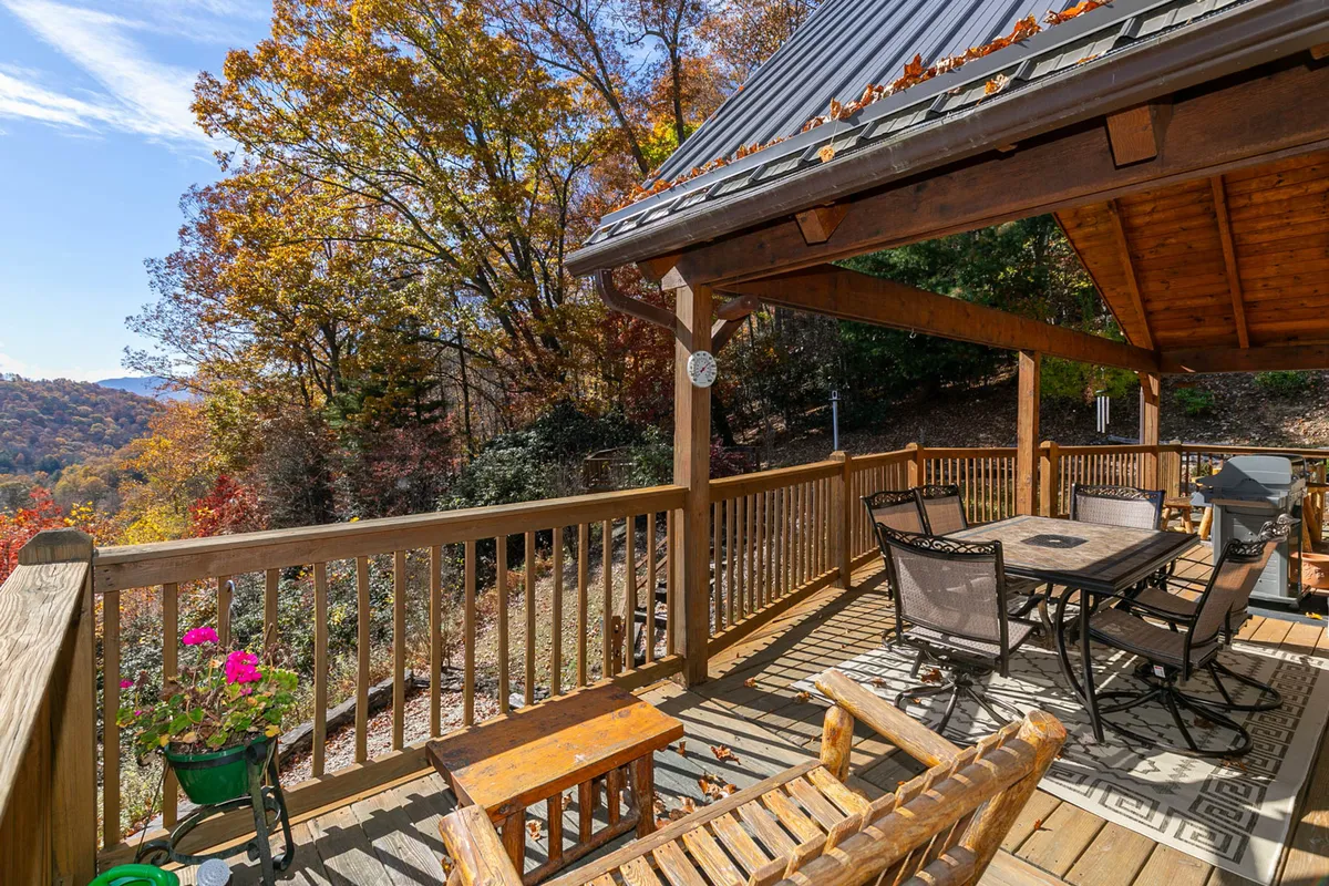 A tranquil wooden deck set among trees, featuring a dining table with chairs—ideal for relaxing, dining, or simply enjoying the view. The setting is serene and private, reinforcing the property’s outdoor living appeal.