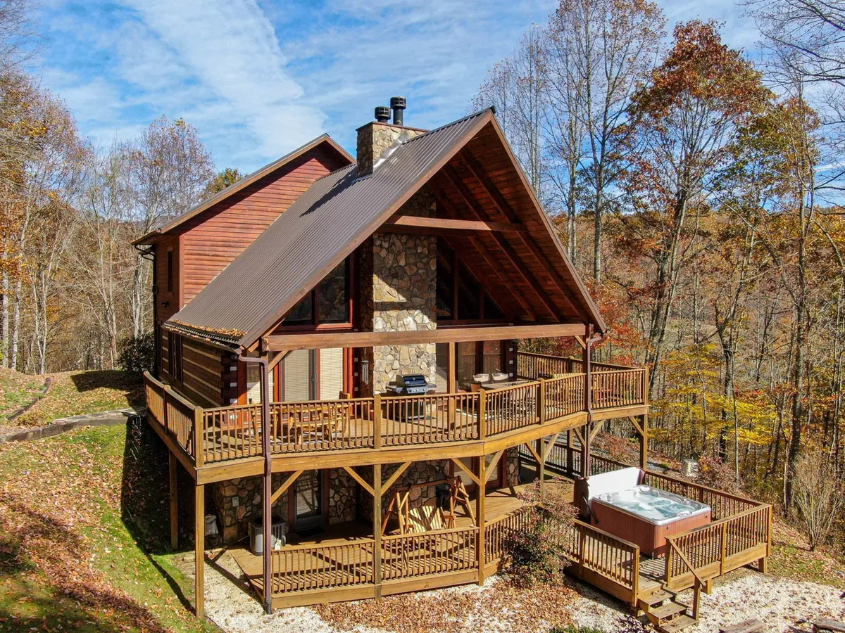 A spacious wooden deck equipped with a hot tub, stone chimney, and surrounded by dense forest. The deck provides opportunities for both relaxation and group activities, from sipping morning coffee to evening stargazing or grilling meals together.